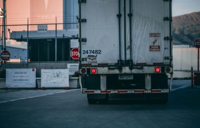 pexels-photo-2449454-2449454 Semi truck parked at a loading dock with visible caution signs and industrial surroundings.